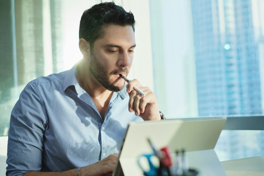 Ex-smoker Man Smoking Electronic Cigarette In Office While Working