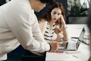 Manager showing employee workplace bullying policy on laptop